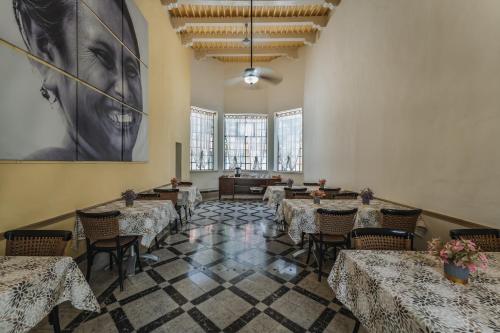 a dining room with tables and chairs and a large painting at Hotel Boutique La Casona by Kavia in Mérida
