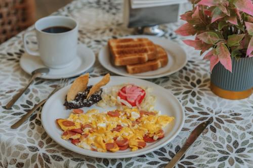 a table with plates of breakfast food and a cup of coffee at Hotel Boutique La Casona by Kavia in Mérida