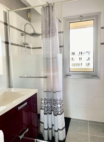 une salle de bain avec un rideau de douche et un lavabo dans l'établissement Résidence Les Huniers - Charmant T3 avec vue imprenable sur le bassin d'Arcachon MAE-9574, à Arcachon