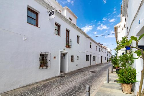 a cobblestone street with white buildings and plants at La Casa de la Iglesia in Mijas