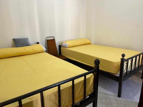 two beds in a room with yellow sheets at White Bay Ras Sedr وايت باي راس سدر in Ras Sedr