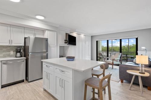 Il comprend une cuisine équipée d'un réfrigérateur et d'une table avec des chaises. dans l'établissement Bayside Villa 5110- Captiva One Bedroom Deluxe Residence, à Captiva