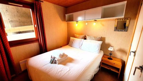 Cette petite chambre comprend un lit avec des draps blancs. dans l'établissement Résidence Chavaniou - T3 au pied des pistes, secteur la Turche MAE-3491, aux Gets