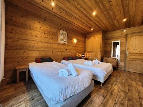 deux lits dans une chambre aux murs en bois dans l'établissement Résidence Beau Sejour - Testez le confort de louer un appartement à deux pas des remontées mécaniques ! MAE-7551, aux Gets
