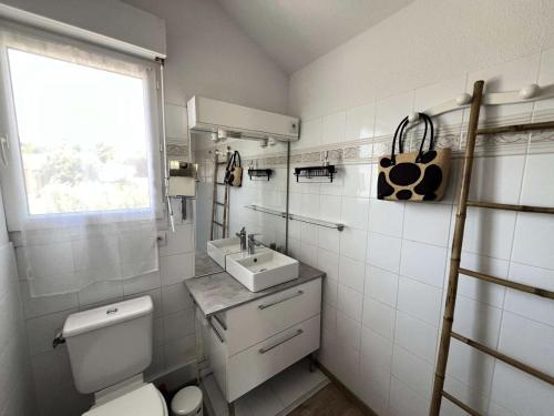 une salle de bain avec toilettes, lavabo et fenêtre dans l'établissement Résidence Les Arros - 087 - Charmante maison sur 2 niveaux aux Arros MAE-6121, à Soulac-sur-Mer