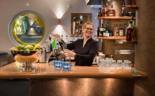 a woman standing behind a bar with a drink at Best Western Hotel zur Post in Bremen