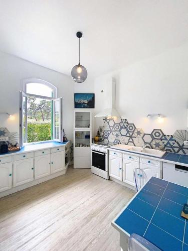 une grande cuisine avec des armoires blanches et une fenêtre dans l'établissement Résidence 05025-lacanau Ocean - Magnifique Canaulaise typique 5 chambres, 10 personnes à Lacanau océan MAE-0561, à Lacanau