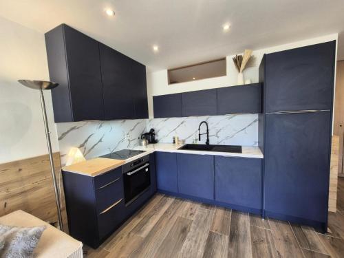 - une cuisine avec des armoires bleu foncé et un évier dans l'établissement Résidence Bec Rouge - Appartement rénové·Skis aux pieds·Balcon MAE-6213, à Tignes