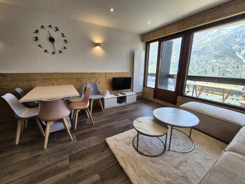 - un salon avec une table, des chaises et une horloge dans l'établissement Résidence Bec Rouge - Appartement rénové·Skis aux pieds·Balcon MAE-6213, à Tignes