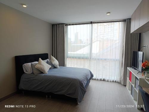 Un dormitorio con una cama y una ventana grande. en Apartaestudio Centro Bogotá, en Bogotá