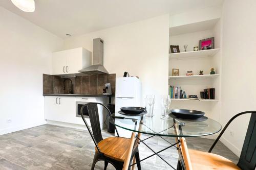 une petite cuisine avec une table et des chaises en verre dans l'établissement Le Midtown - By BEST KEYS - Idéal Pro & Couple - Grande Terrasse & Lumineux - Centre-Ville - Smart TV Netflix & WiFi Fibre - Check-in Autonome - Parking Facile - Calme & Confort Premium, à Tonnerre