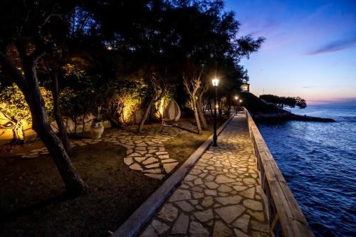 a sidewalk next to the water at night at Seaside Villa Margarita in Akrotiri