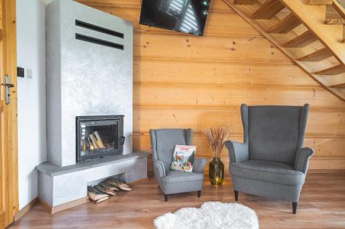 two chairs in a living room with a fireplace at Domki Krupa Chochołów 400 m od terem in Chochołów