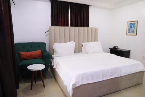 a bedroom with a bed and a green chair at Serviced Apartment Direct in Abuja