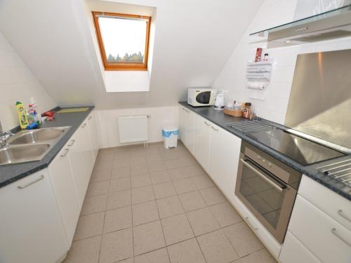a kitchen with white cabinets and a sink and a window at Comfortable Apartment in Nemojov near Forest in Horní Nemojov