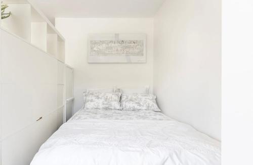 a white bedroom with a bed with white sheets at Modern apartment ONLY 5 minutes from City centre in Bergen