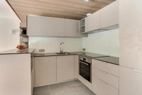 a kitchen with white cabinets and a sink at Résidence La Suite - Magnifique appartement 3 pièces cabine situé à Méribel centre proche des commerces et des pistes de ski MAE-6403 in Les Allues