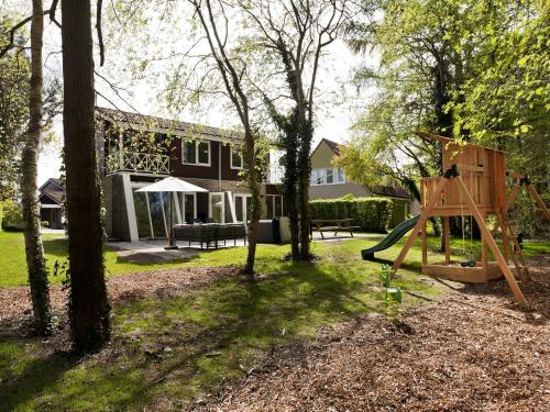 a yard with a playground and a house at Comfortable family and friends house with wellness in Vlagtwedde