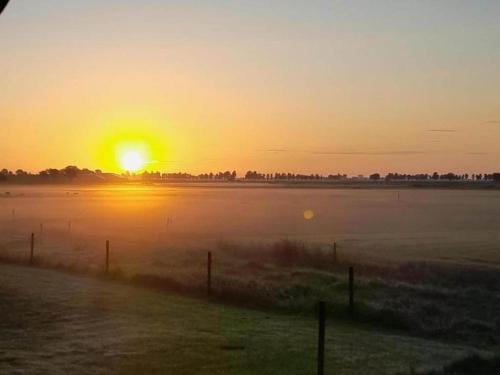 a sunrise over a field with the sun in the sky at Villa in Friesland with Sauna and Jetty in Idskenhuizen