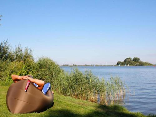 a person laying in a bag next to a body of water at Villa in Friesland with Waterfront Jetty in Idskenhuizen