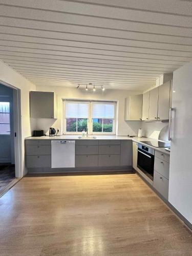 a large kitchen with white cabinets and a wooden floor at Feriehus Broløkken Rudkøbing in Rudkøbing