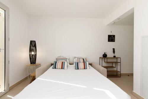 une chambre blanche avec un grand lit blanc avec des oreillers dans l'établissement CALYPSO- Superbe perle, Vieil Antibes, wifi, climatisation, à Antibes