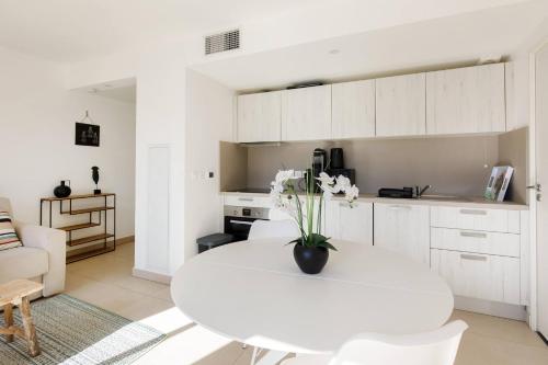 - une cuisine blanche avec une table blanche et des fleurs dans l'établissement CALYPSO- Superbe perle, Vieil Antibes, wifi, climatisation, à Antibes