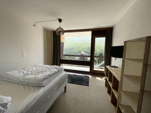 une chambre avec un lit et une grande fenêtre dans l'établissement Résidence Jandri - Super T3 à proximité des pistes et commodité, avec piscine de résidence MAE-5181, à Les Deux Alpes