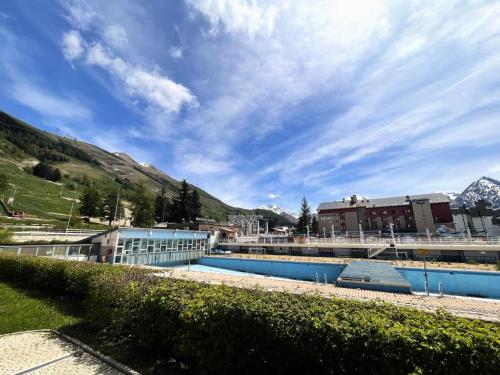 un complexe avec une piscine avec des montagnes en arrière-plan dans l'établissement Résidence Vallee Blanche - Superbe studio contemporain au cœur de station MAE-5281, à Vénosc