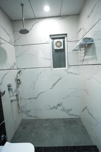 a bathroom with white marble walls and a window at Masaga by Qcent, Gurugram in Gurgaon