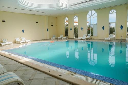 una grande piscina in una grande stanza con sedie di Hôtel Excel KHIMA a Yasmine