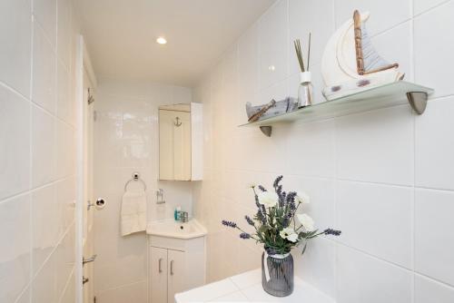 une salle de bain avec un vase de fleurs sur un lavabo dans l'établissement Dolls Cottage, à Looe
