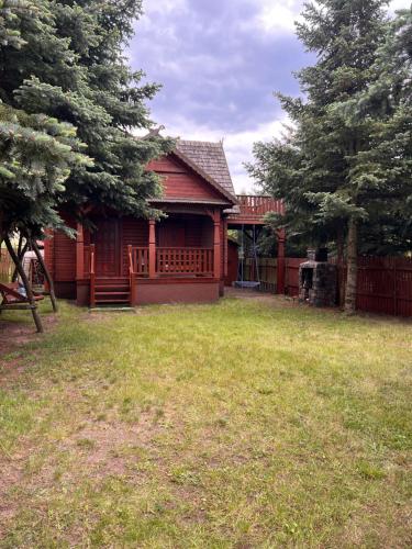a red house with a fence and a yard at Hello Kurpie in Nowogród