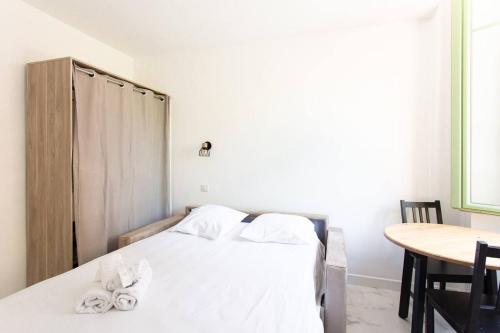 - une chambre avec un lit avec des draps blancs et une table dans l'établissement LYMPIA -Cosy studio, 200 m plages de Nice - Le Port, à Nice