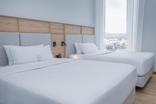 two white beds in a room with a window at Oro Verde Portoviejo in Portoviejo