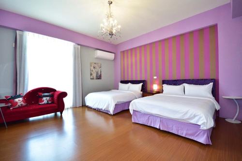 a purple room with two beds and a red chair at Mary B&B瑪莉年代-親子友善 租車優惠 近火車站 可包棟 電動麻將 BBQ KTV in Taitung City