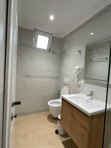 a bathroom with a sink and a toilet and a window at Odore di Mare 2 in Qeparo