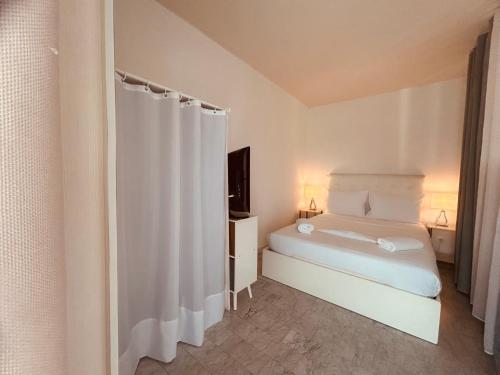 - une chambre blanche avec un lit et un rideau dans l'établissement L'Estivalière, à La Celle-sous-Gouzon