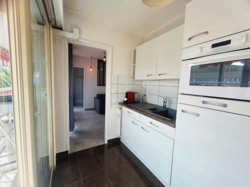 une cuisine avec des armoires blanches et un évier dans l'établissement L'Estivalière, à La Celle-sous-Gouzon