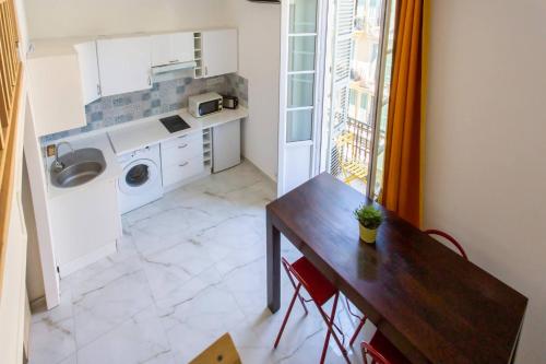 une cuisine avec une table et une machine à laver dans l'établissement GIOA- Studio avec balcon, place Garibaldi -Paillon, à Nice