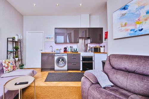 a living room with a couch and a kitchen at West Beach 1 - dog friendly - Portrush by the Sea in Portrush