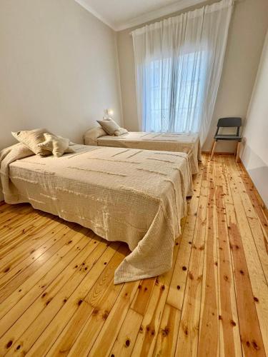 a bedroom with two beds and a wooden floor at CAL QuEROL LlíViA - Piscina in Llivia