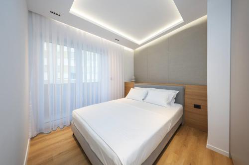 a bedroom with a white bed and a large window at Premium Centre Apartment in Peje