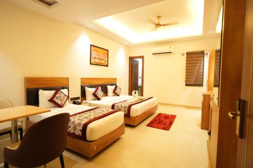 a hotel room with two beds and a desk and a table at Hotel MASAGA by QCENT in Gurgaon
