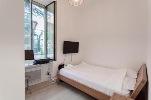 une chambre blanche avec un lit et une télévision dans l'établissement ROSIE-Charmant Cocon à Beausoleil, aux Portes de Monaco, à Beausoleil