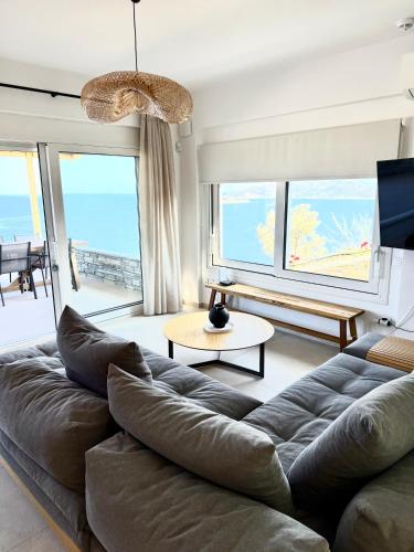 a living room with a couch and views of the ocean at PETRA Luxury Villas in Áyioi Apóstoloi