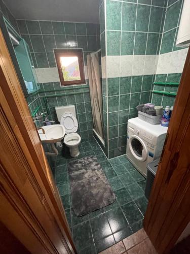 a green tiled bathroom with a toilet and a sink at Vikendica Savić in Šipovo