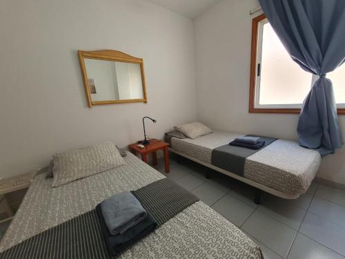 two beds in a room with a mirror and a window at Alquilaencanarias-Medano Galte, terrace and beach in El Médano