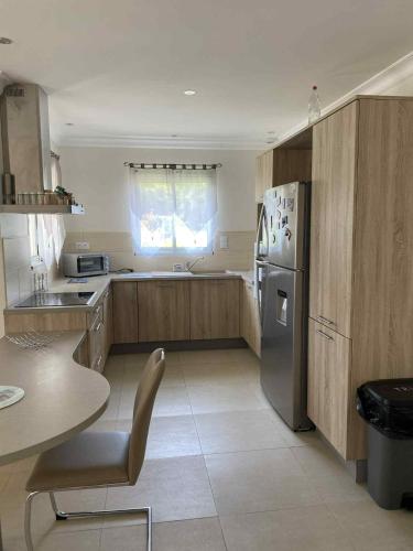 une cuisine avec un réfrigérateur en acier inoxydable et une table dans l'établissement Maison vacances - cure thermale, à Eugénie-les-Bains