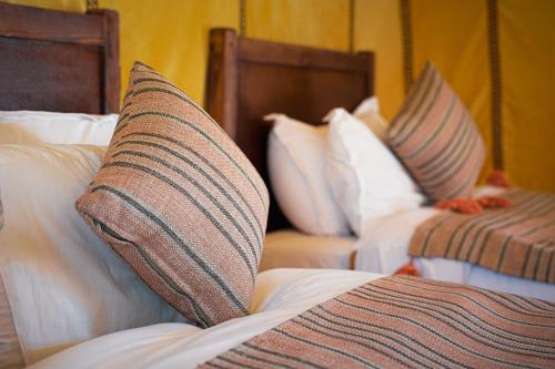 two beds with pillows on them in a hotel room at Najma Luxury Camp in Merzouga